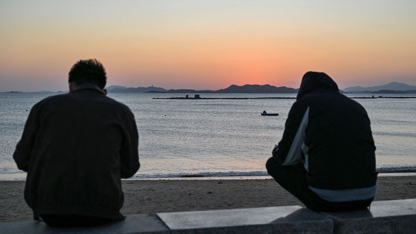 Två män sitter på stranden på ön Pingtan, den punkt tillhörande Folkrepubliken Kina som ligger närmast Taiwan. Kablarna mellan Taiwan och fastlandet är en svag punkt. Foto: Adek Berry/AFP via Getty Images